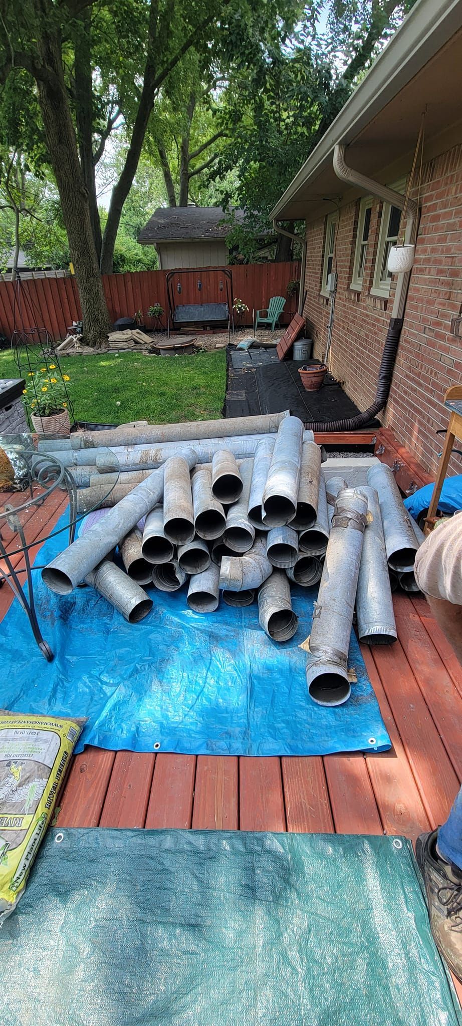 A pile of pipes sitting on top of a blue tarp on a patio.