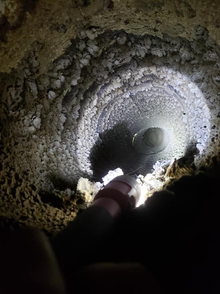 A person is holding a flashlight in a hole in the ground.