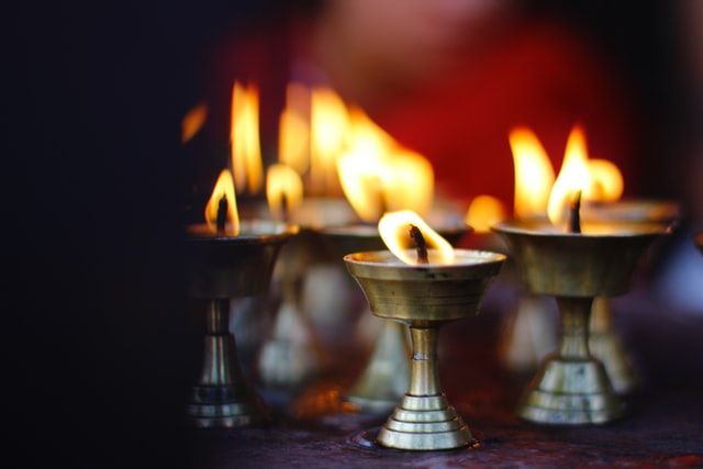 a group of candles are lit up in brass cups