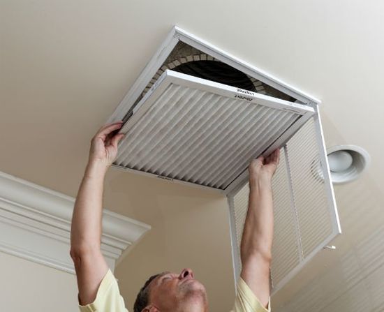 Reaching up to open filter holder for air conditioning filter in ceiling