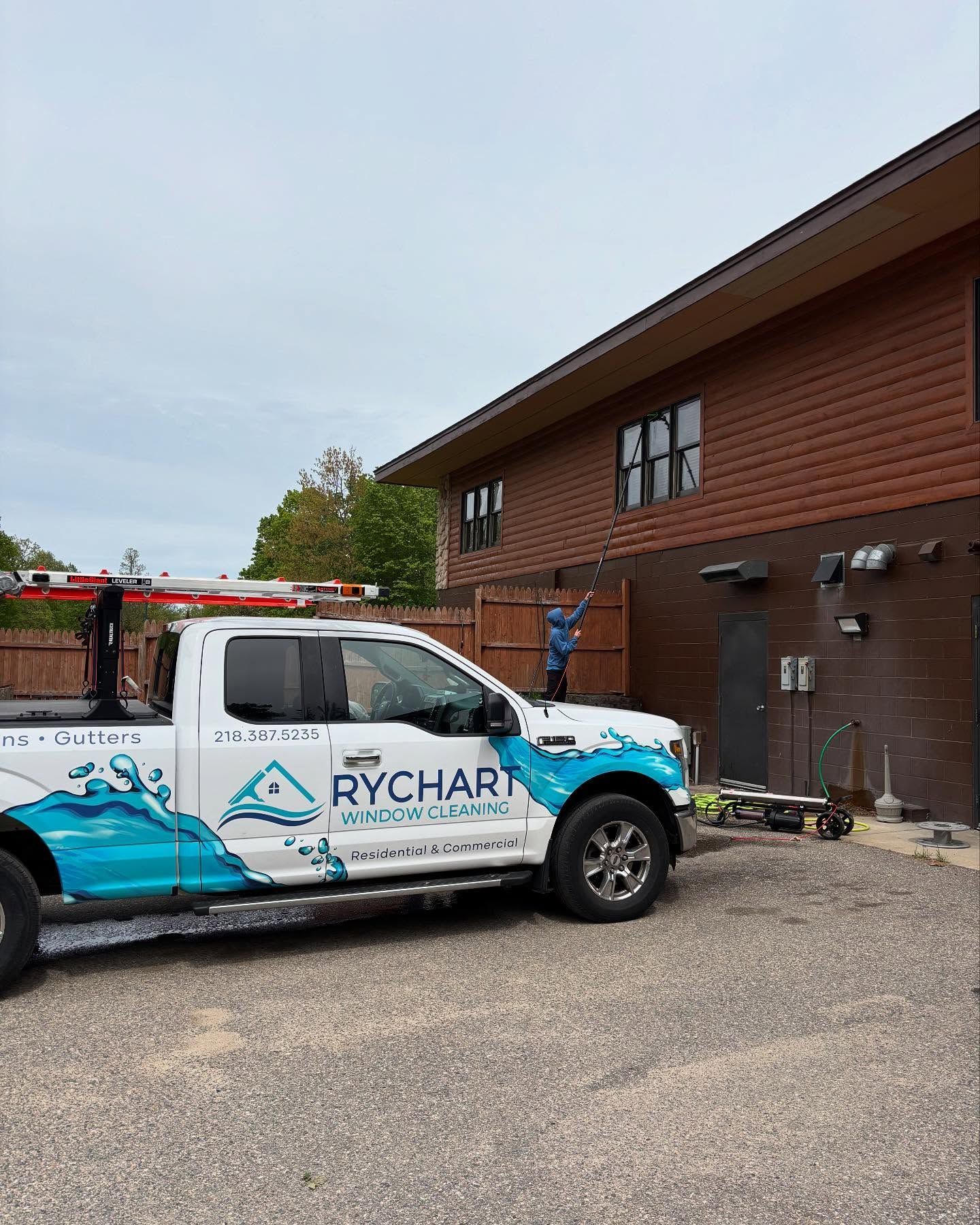 A white Rychart truck parked outside a brick building. A worker stands near the truck.