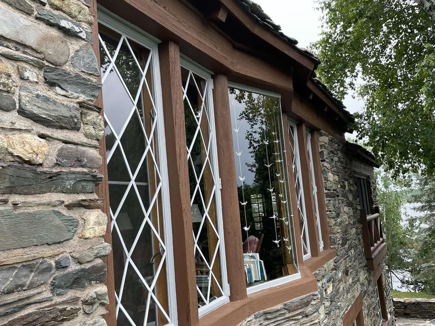 Stone building exterior with diamond-paned windows and brown trim.