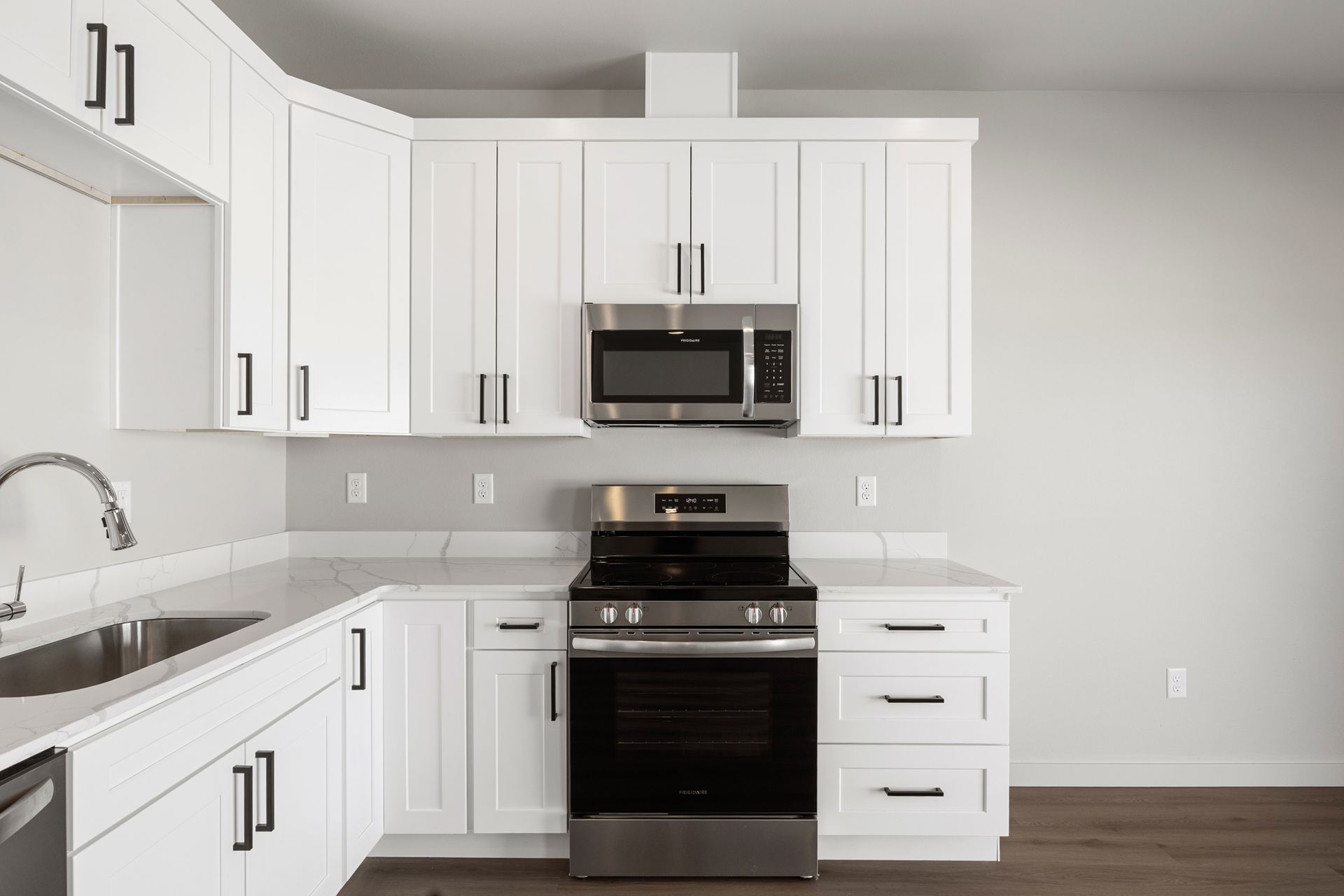 White kitchen with stainless steel appliances and black hardware.