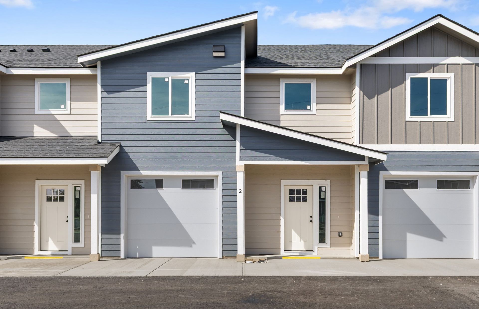 Row of modern townhouses with garages and varied exterior colors.