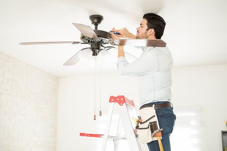 man on the ladder installing ceiling fan