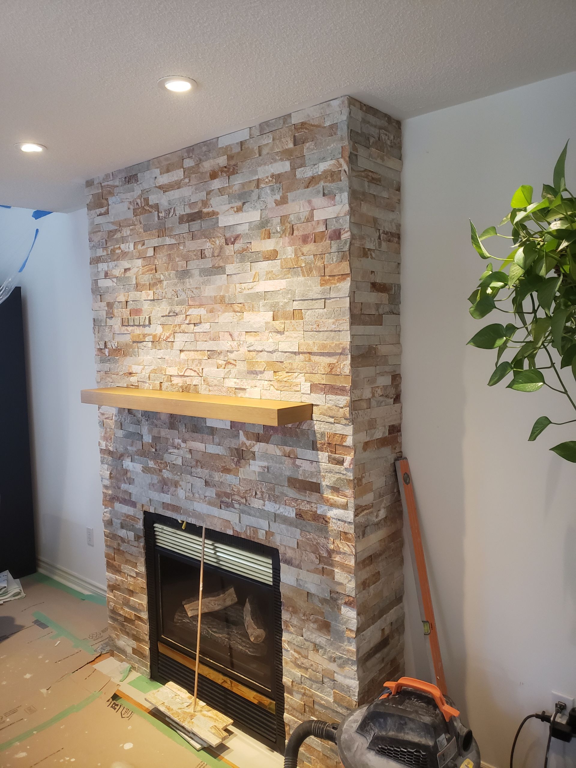 Fireplace with stone facade and wooden mantel in a room.