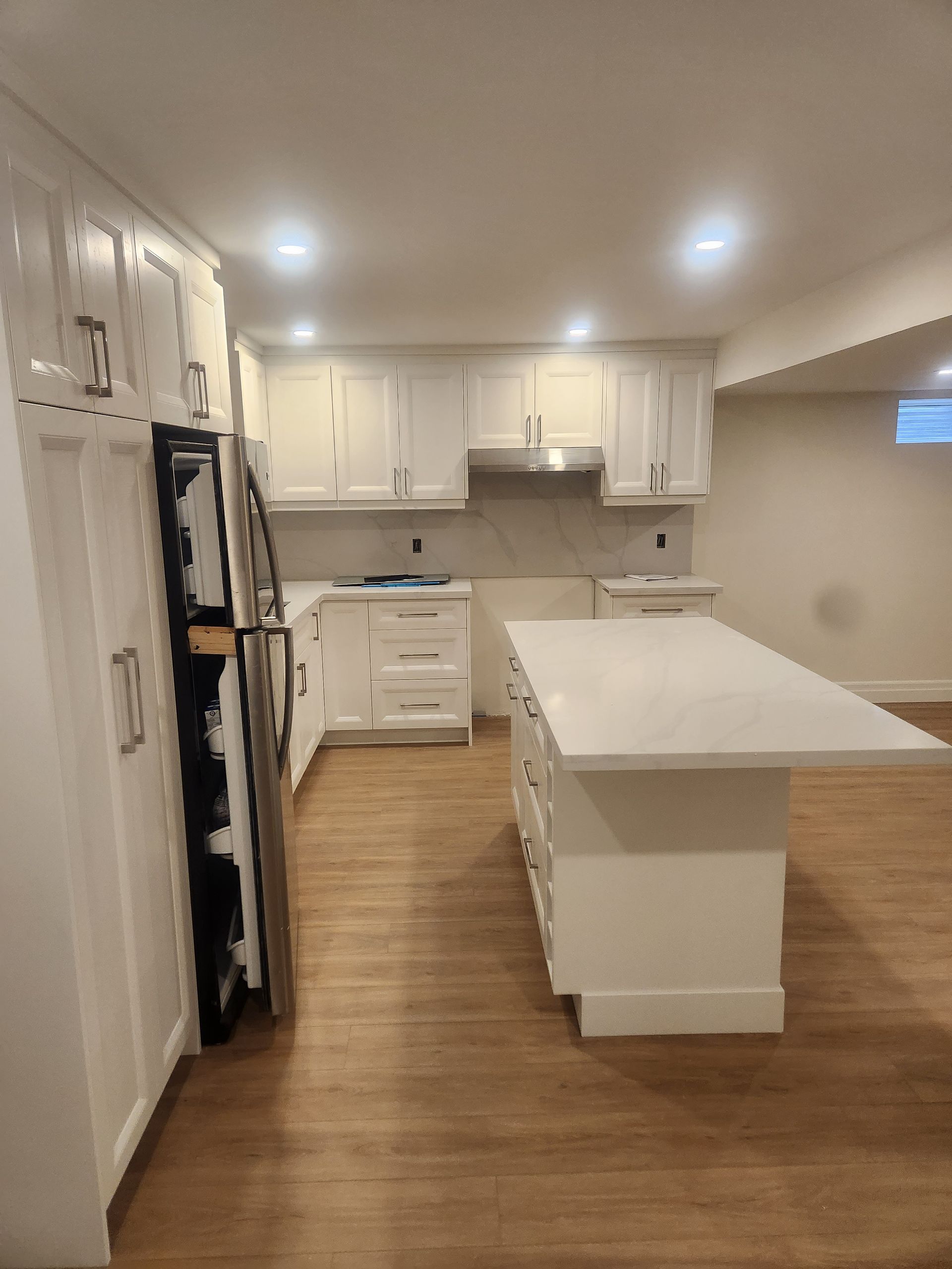 Newly renovated kitchen with white cabinets, island, and stainless steel appliances.