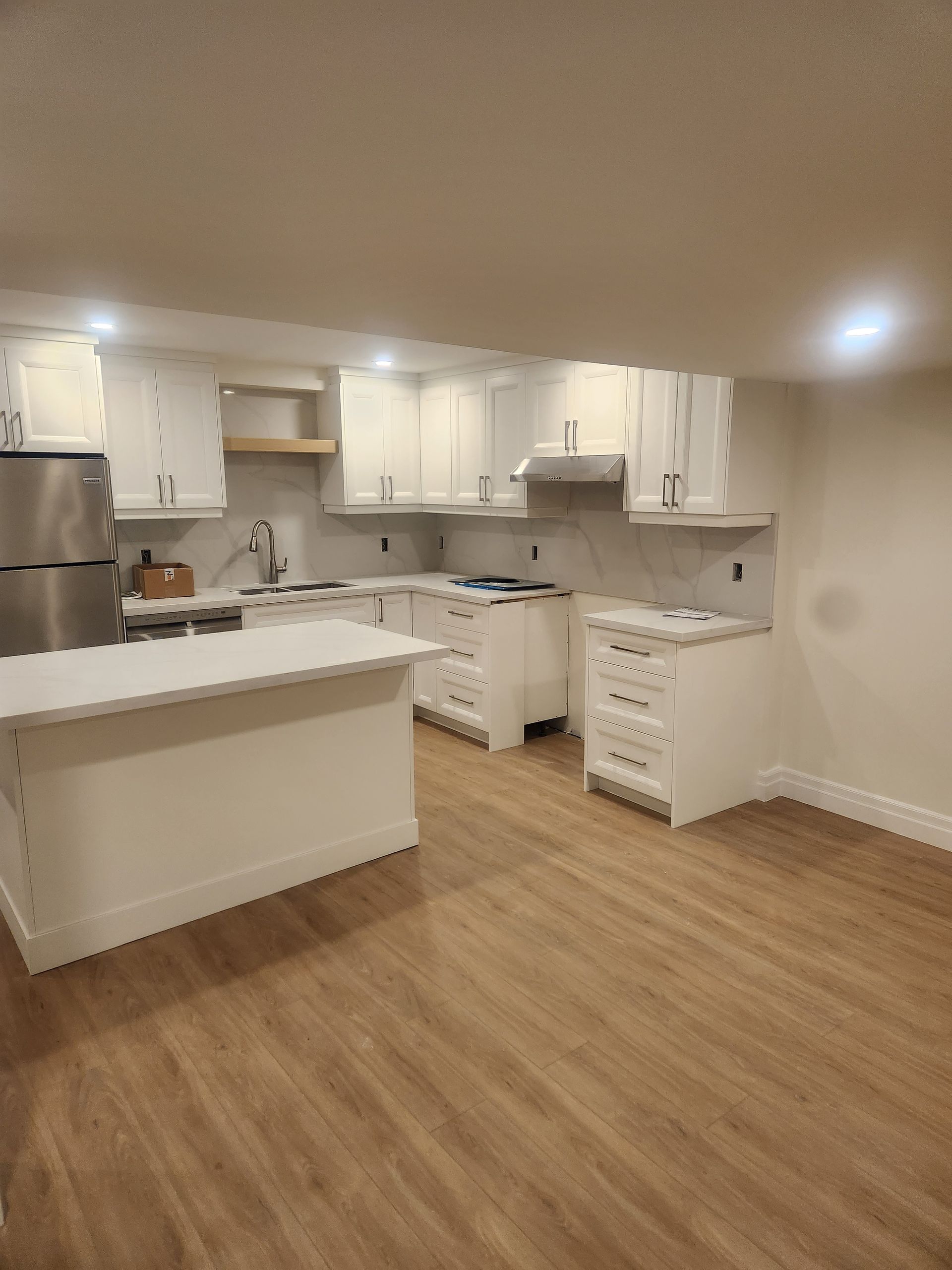 White kitchen with cabinets, countertops, and island; light wood floor.