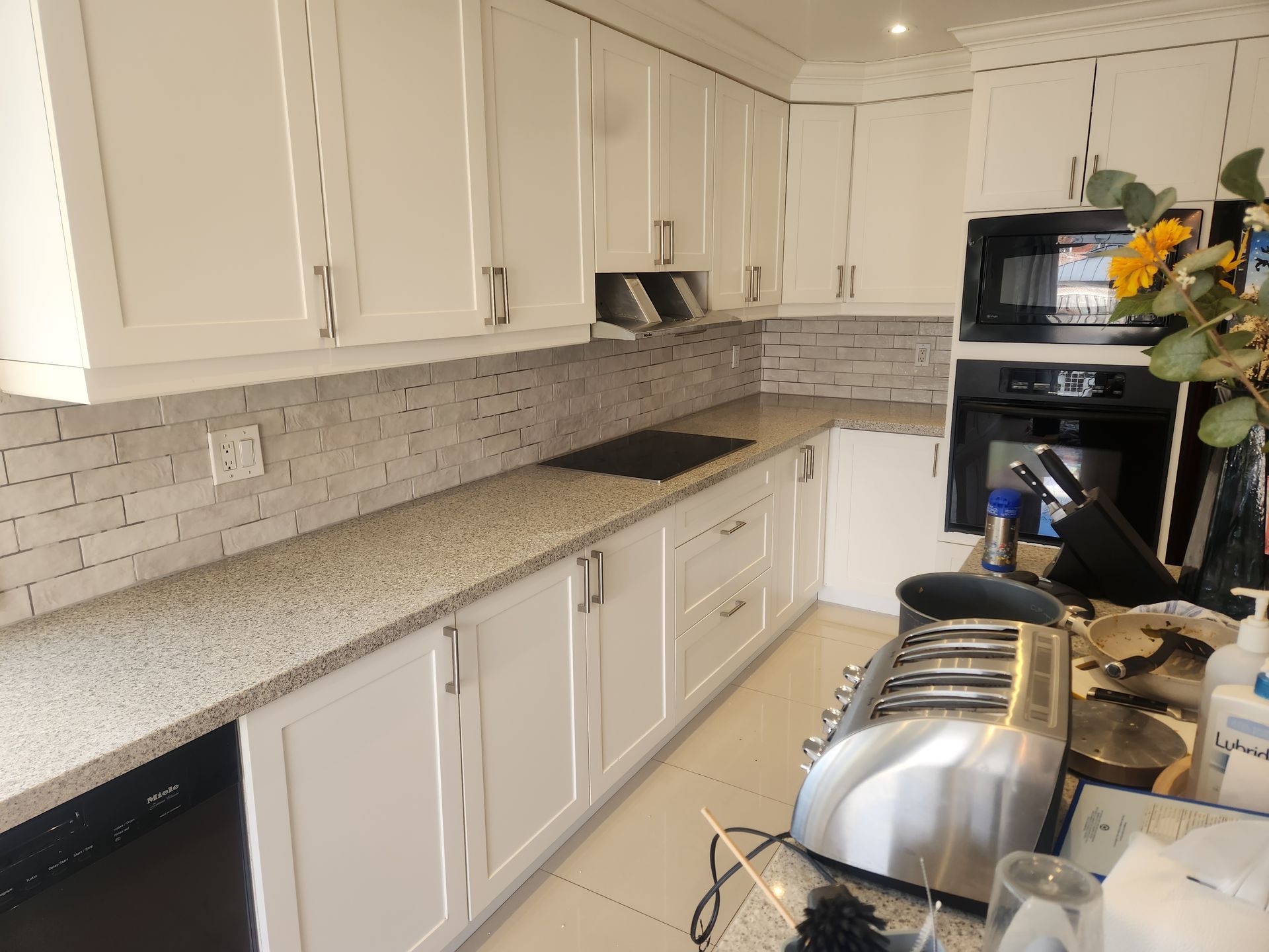 White kitchen with countertop, cabinets, appliances, and mosaic backsplash.
