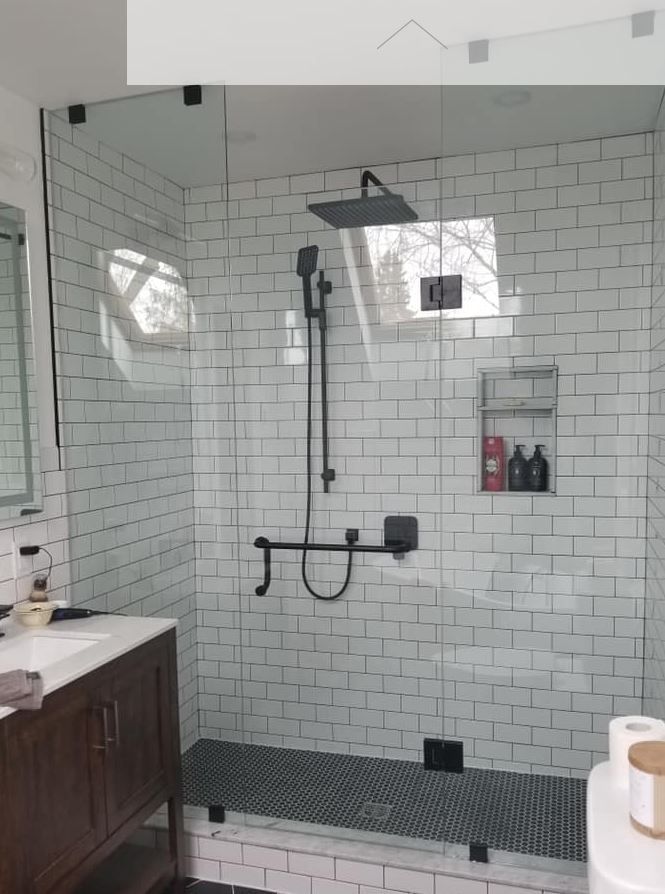 Modern shower with white brick tiles, glass walls, and black fixtures.