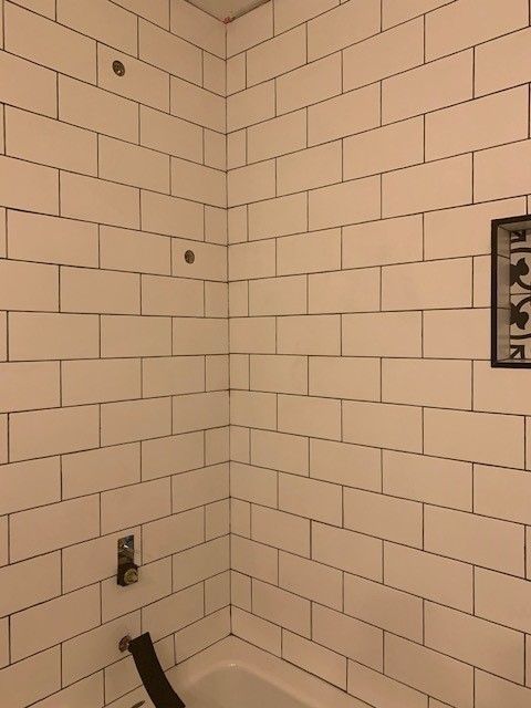 White subway tile shower, corner view, with dark grout lines.