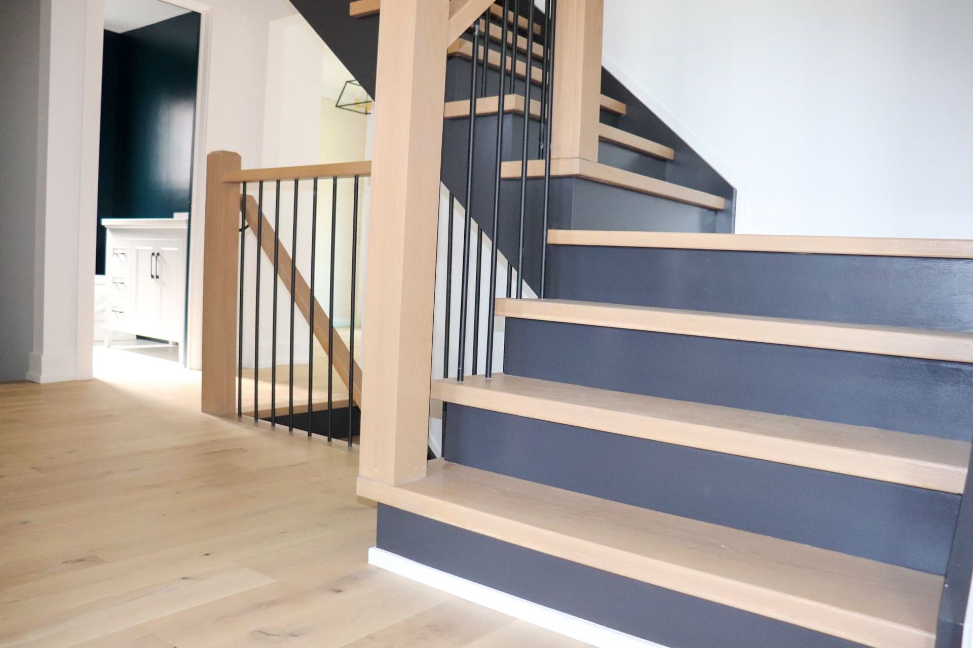 Wooden staircase with black accents and black metal railing.