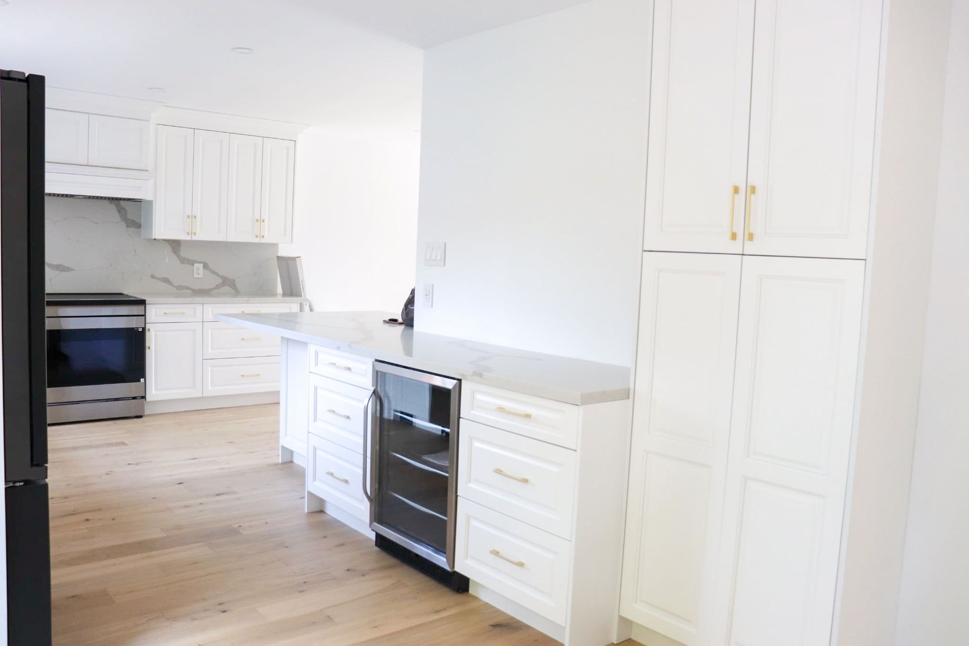 White kitchen with light wood floors, stainless steel appliances, and white cabinets.