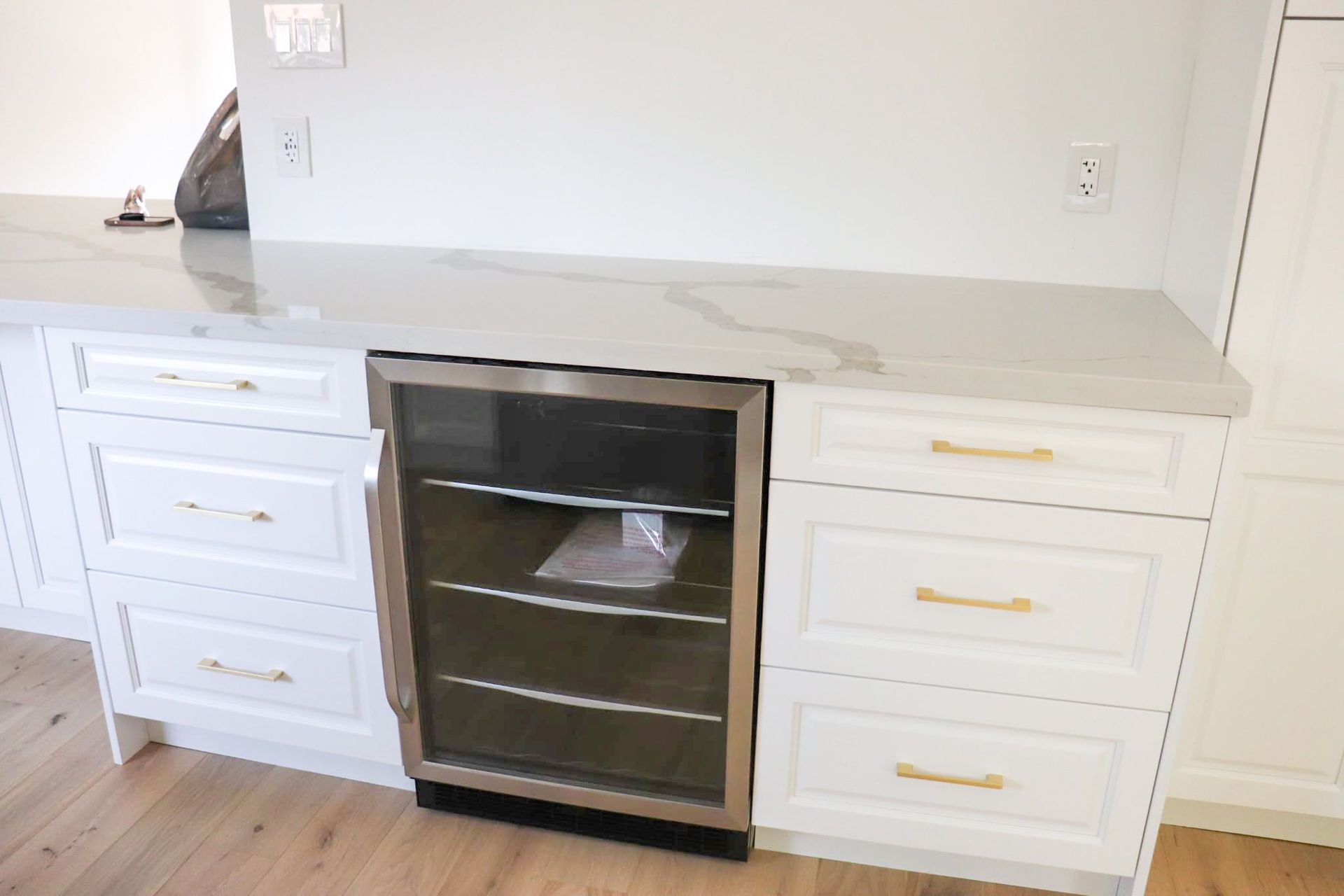 White cabinets with gold hardware, a wine cooler, and a countertop.
