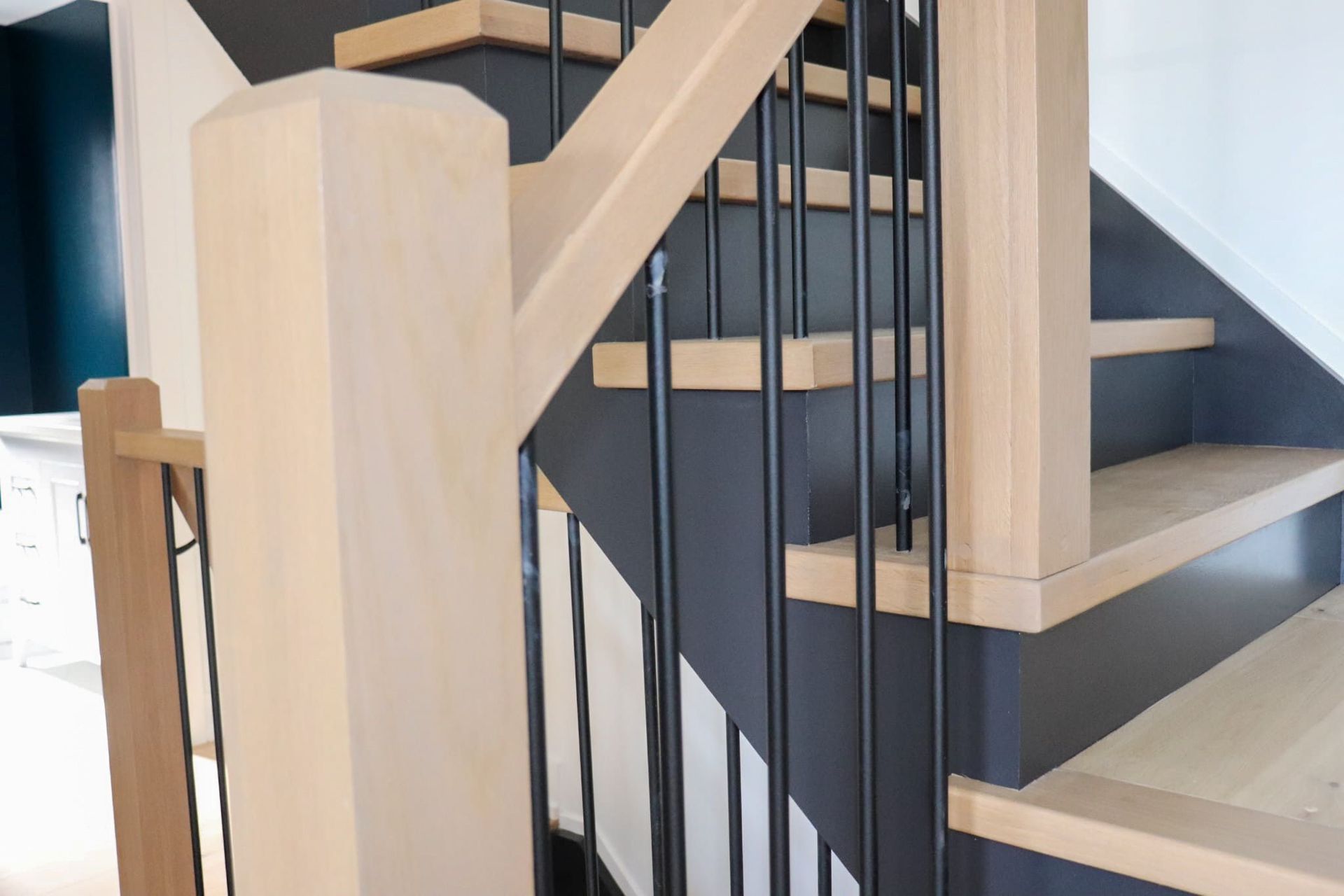 Wooden staircase with black metal railings and dark blue wall accents.