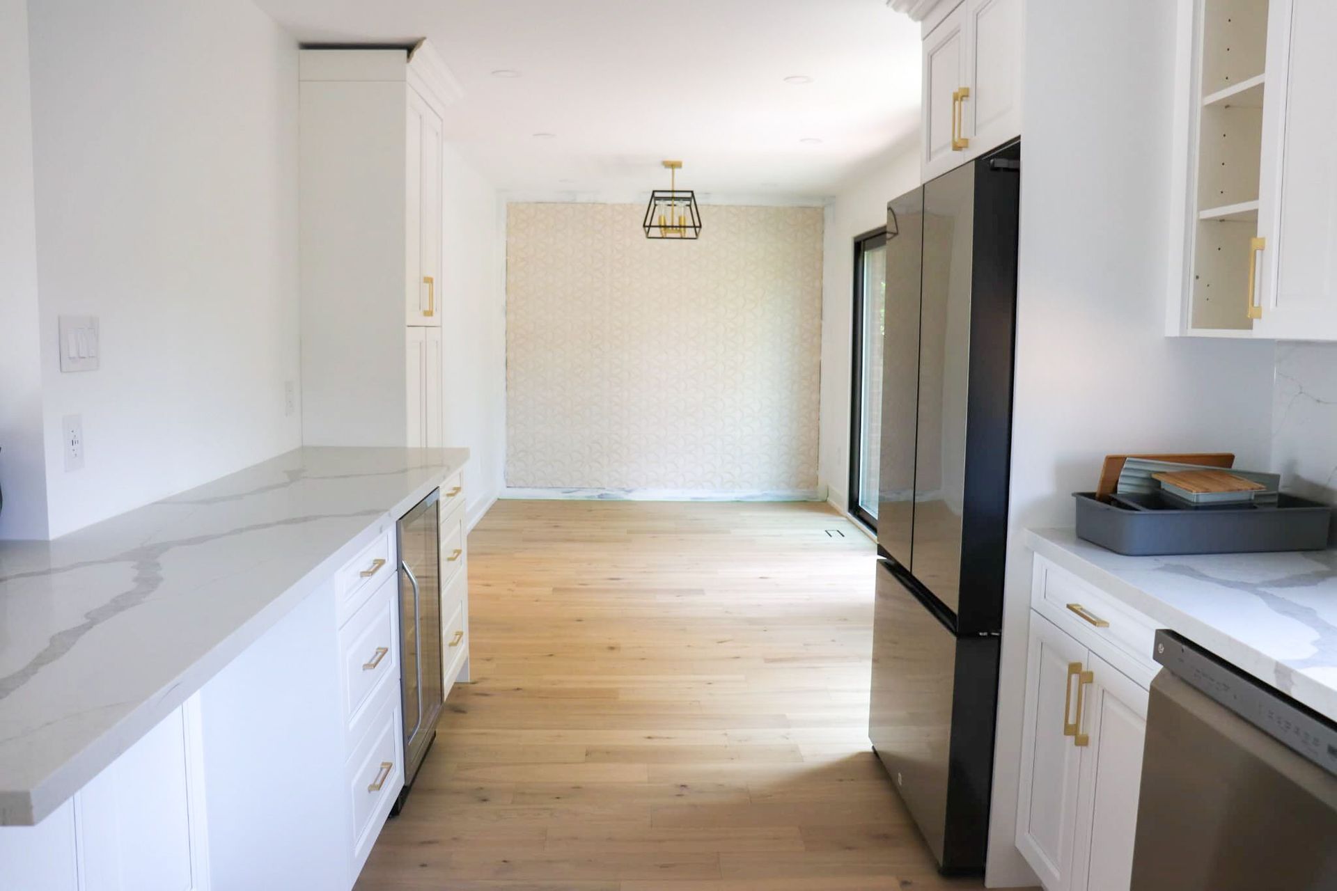 White kitchen with light wood floors, white cabinets, and a black refrigerator.