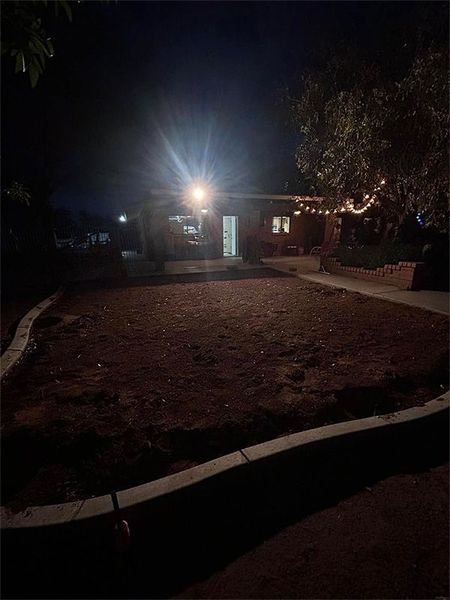 A house is lit up at night with a lot of lights in the yard.