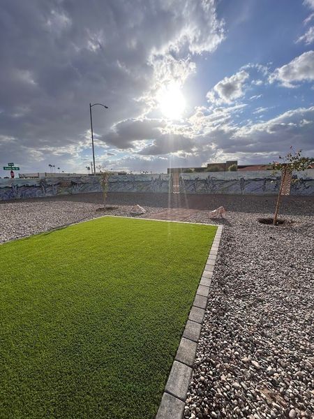 The sun is shining through the clouds over a grassy field.