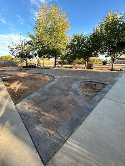 A concrete walkway leading to a patio with trees in the background.