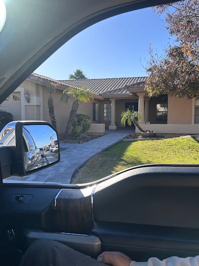 A person is sitting in a car looking out the window at a house.