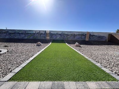 A grassy path leading to a wall with a mural on it.