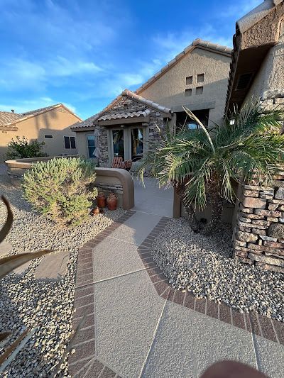 A brick walkway leading to a house with a palm tree in front of it.