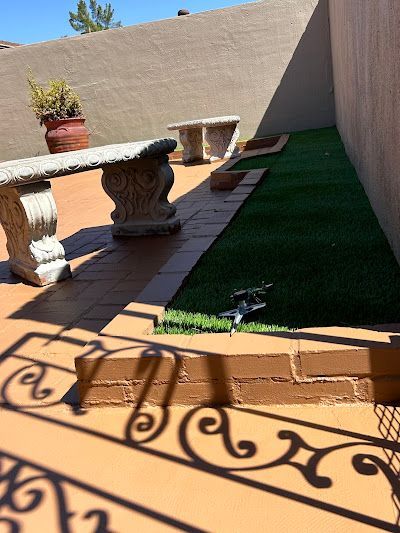 A patio with a bench and a shadow of a wrought iron railing