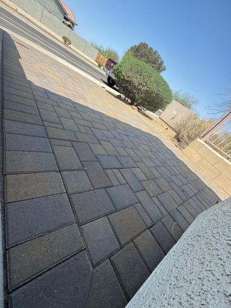A brick walkway with a car parked on the side of the road.