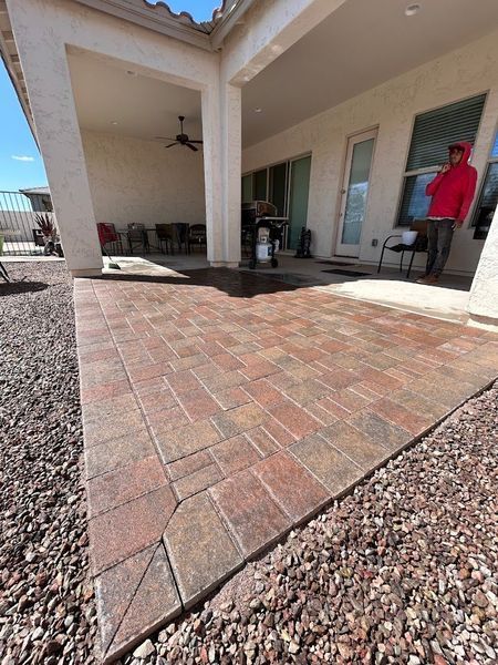 A man in a red hoodie is standing on a patio next to a house.