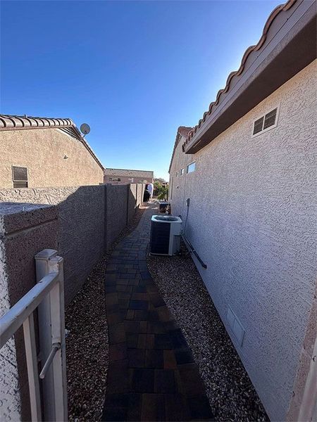 A brick walkway between two houses with a fence