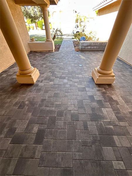 A brick walkway leading to a house with columns