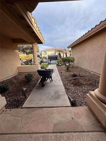 A wheelbarrow is sitting on a sidewalk next to a house.