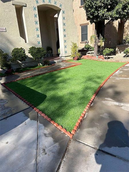 A lawn with a red brick border is in front of a house.