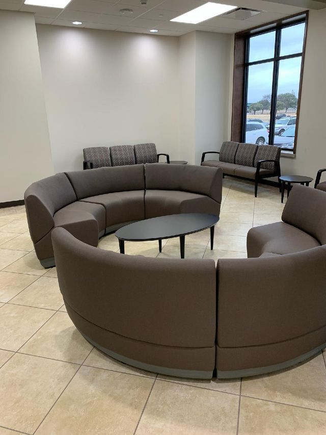 A waiting room with a round couch and a coffee table.
