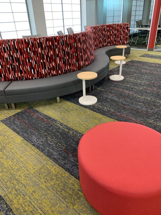 There is a red ottoman in the middle of the room.