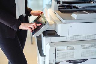 A woman is using a copier in an office.