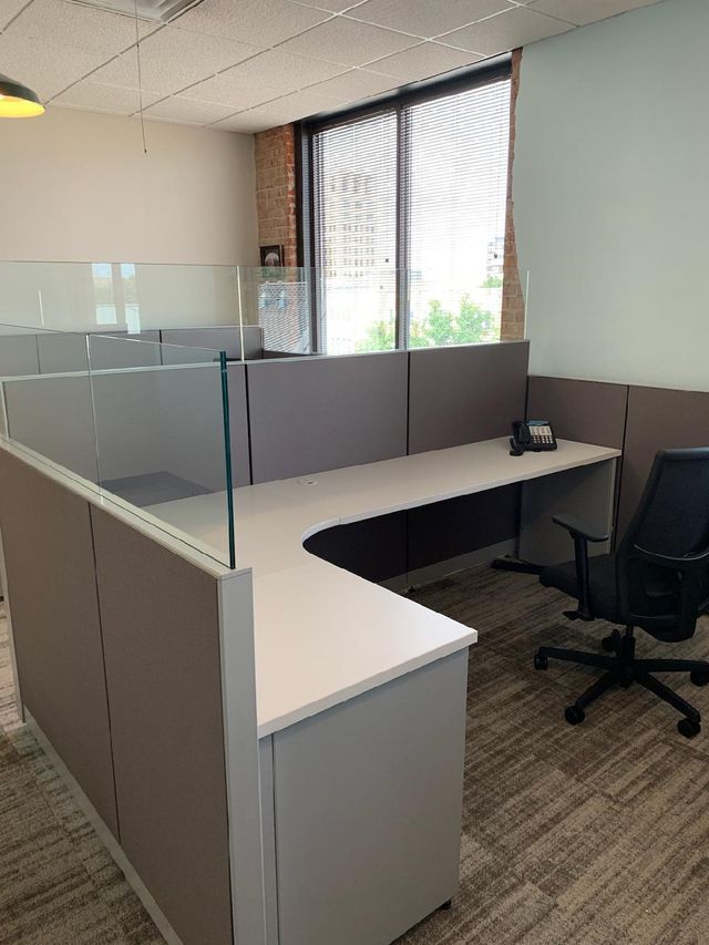 A cubicle with a desk and a chair in an office.