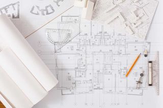 A blueprint of a house with a pencil , ruler , and compass on a table.