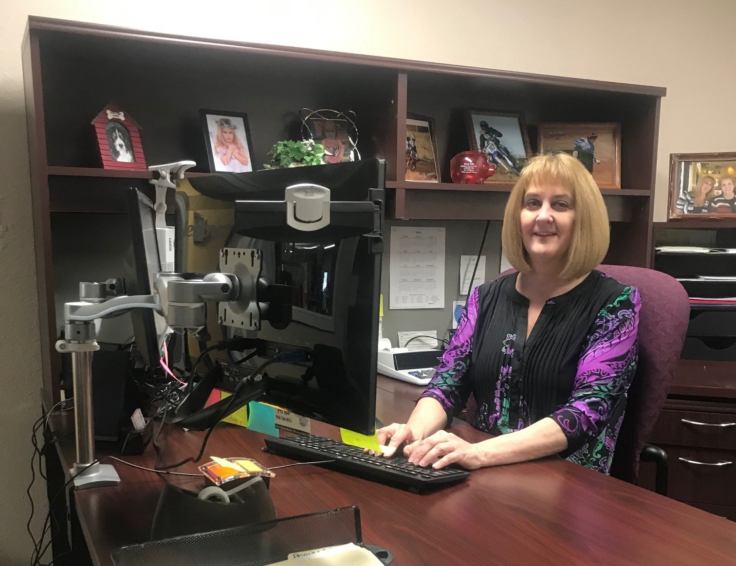 A woman is sitting at a desk in front of a computer.