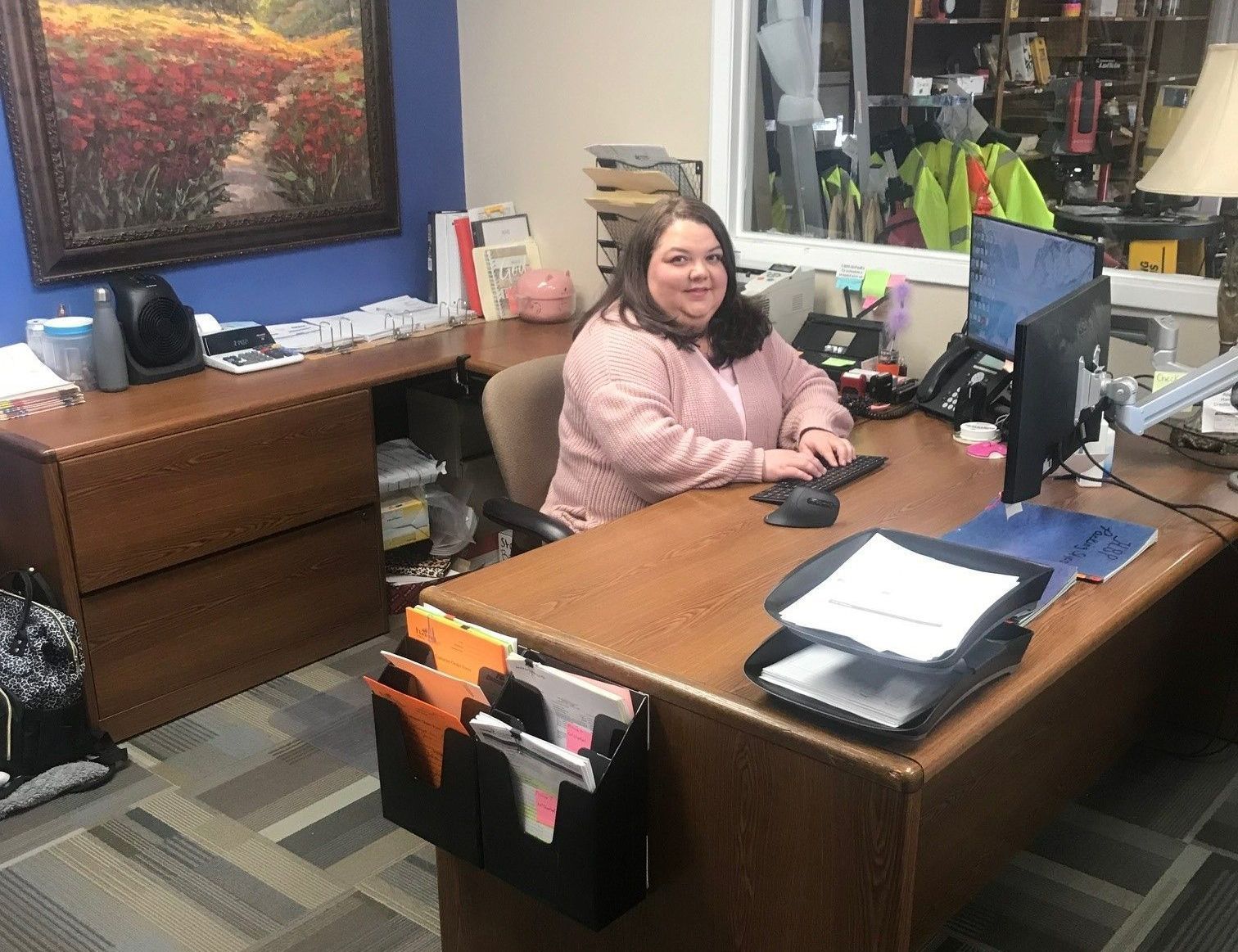 A woman is sitting at a desk in front of a computer.