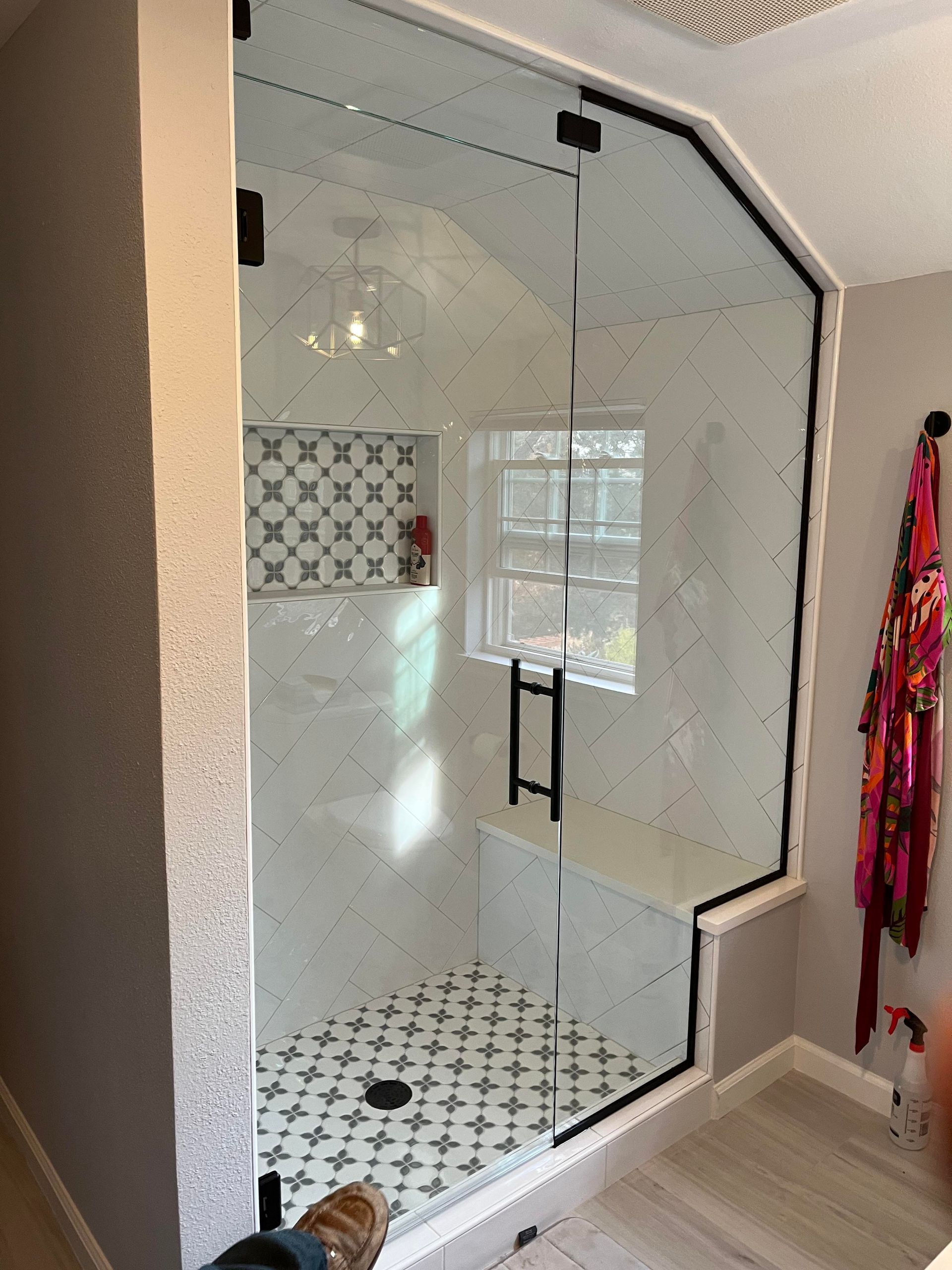 A bathroom with a glass shower door and a window.