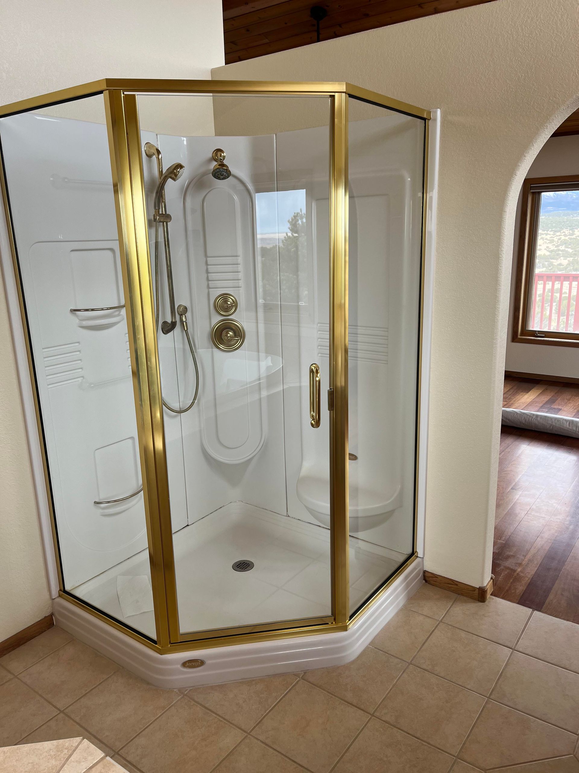 A bathroom with a shower with a gold frame