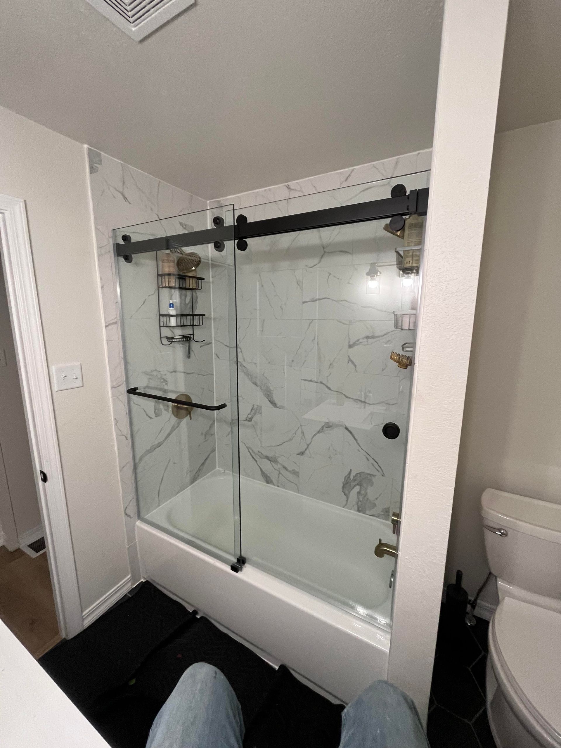 A bathroom with a bathtub , toilet , and sliding glass shower door.