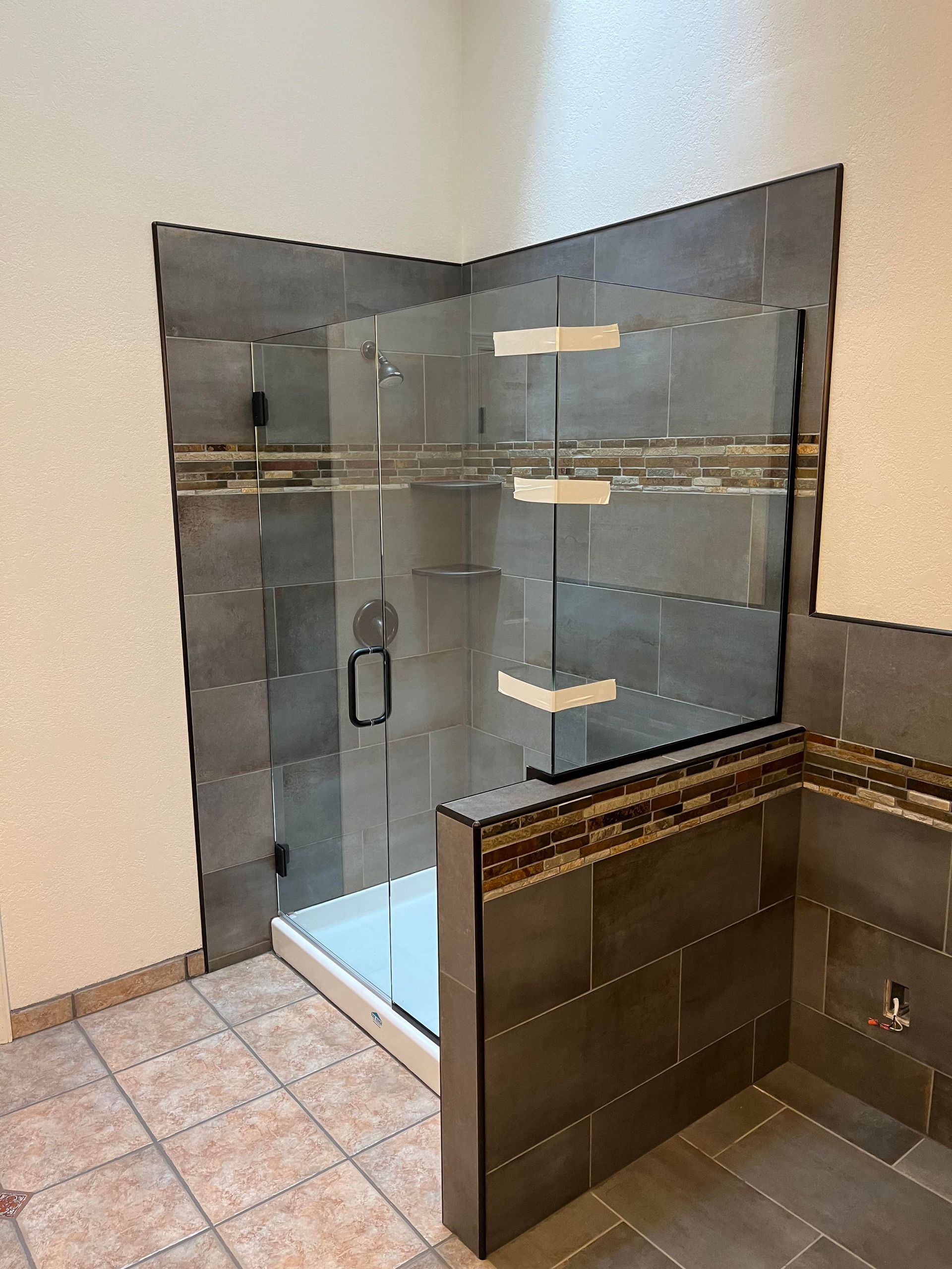 A bathroom with a walk in shower and a glass door.