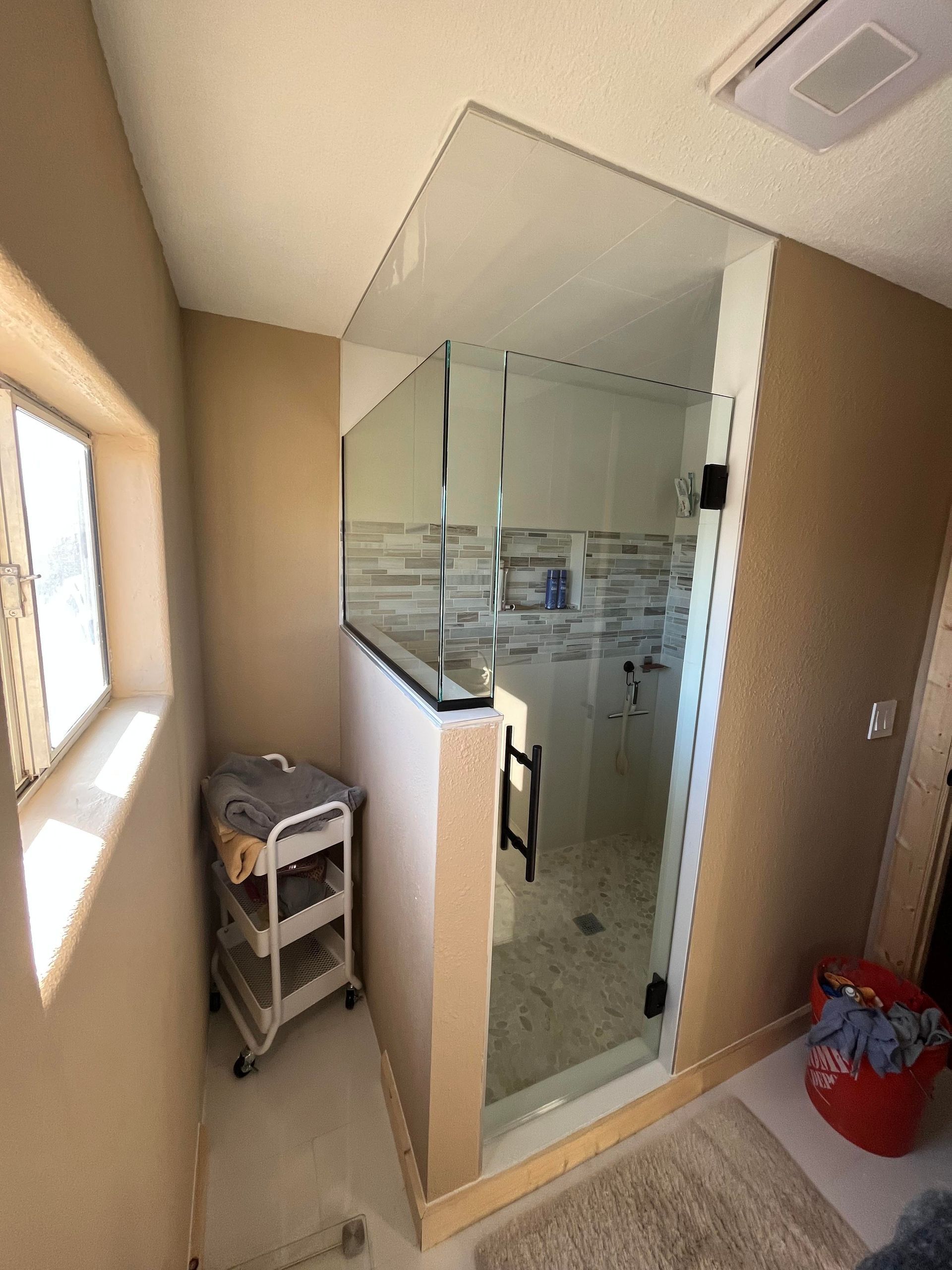 A bathroom with a walk in shower and a window