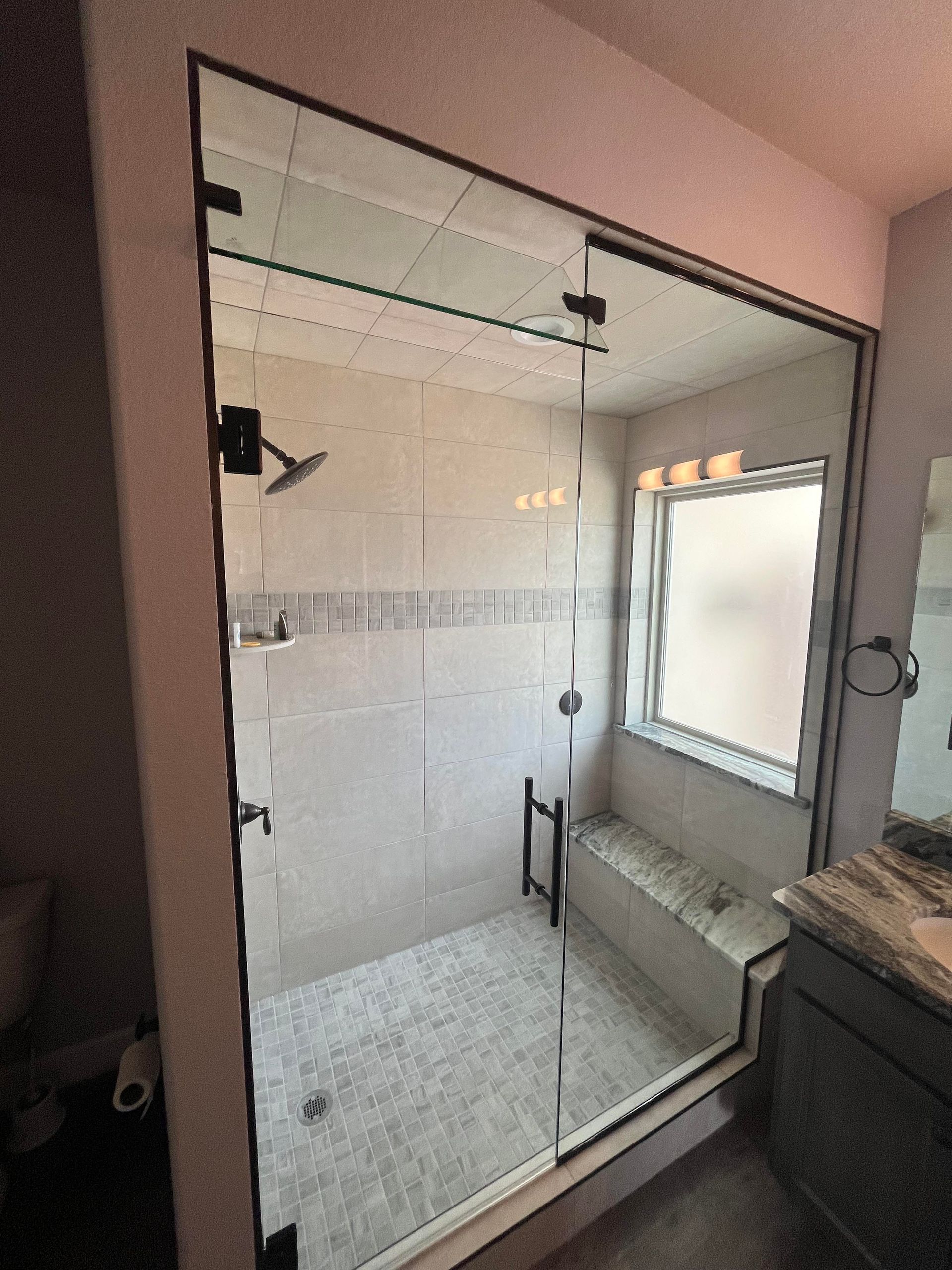 A bathroom with a walk in shower and a window.
