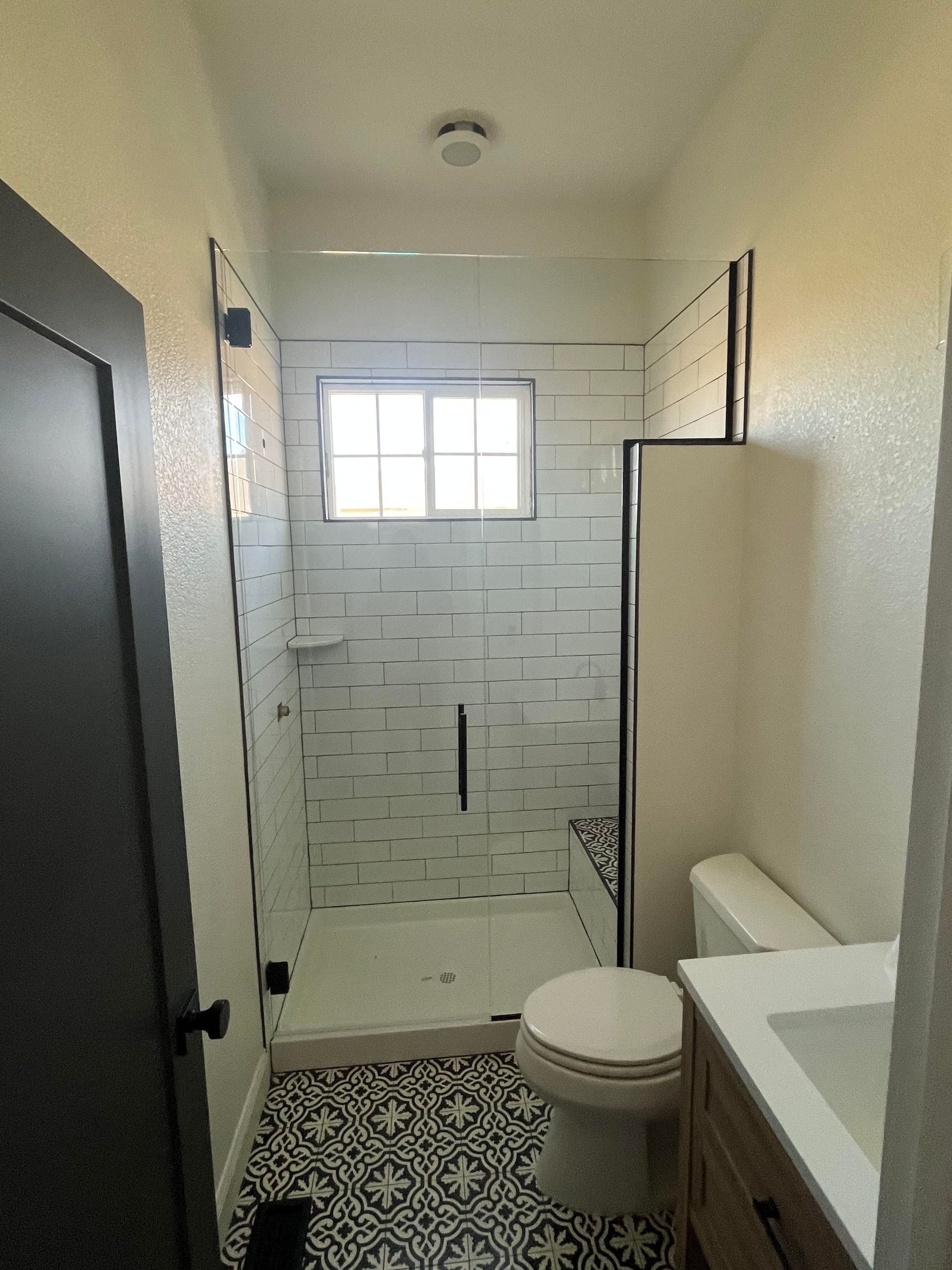 A bathroom with a toilet , sink , shower and window.