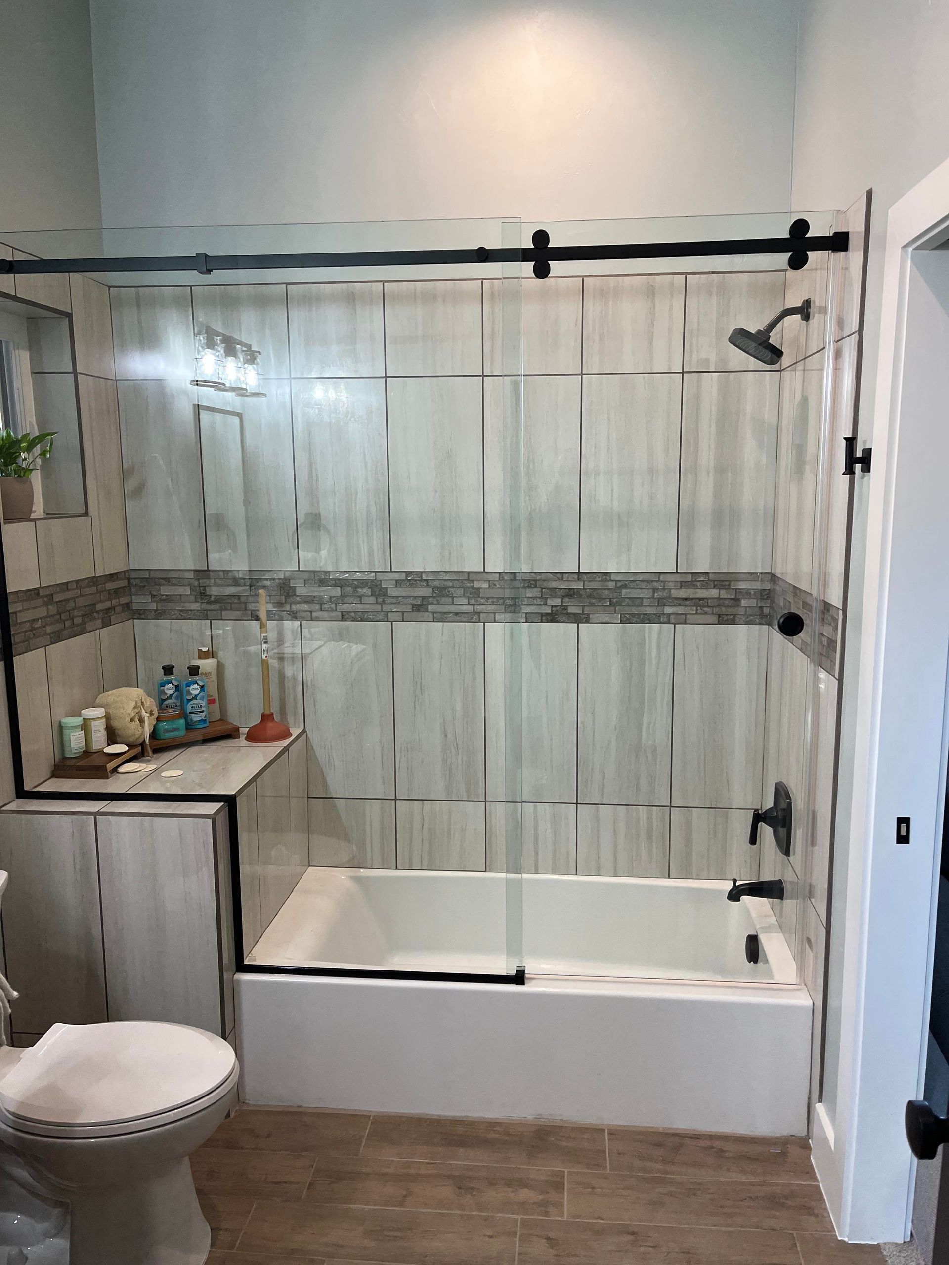 A bathroom with a tub , toilet , mirror and shower.