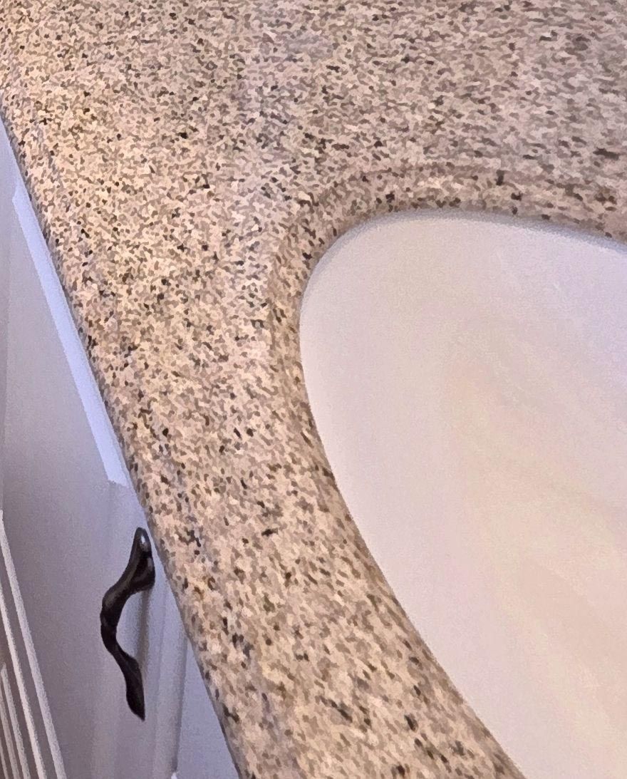 A bathroom sink is sitting on top of a granite counter top.
