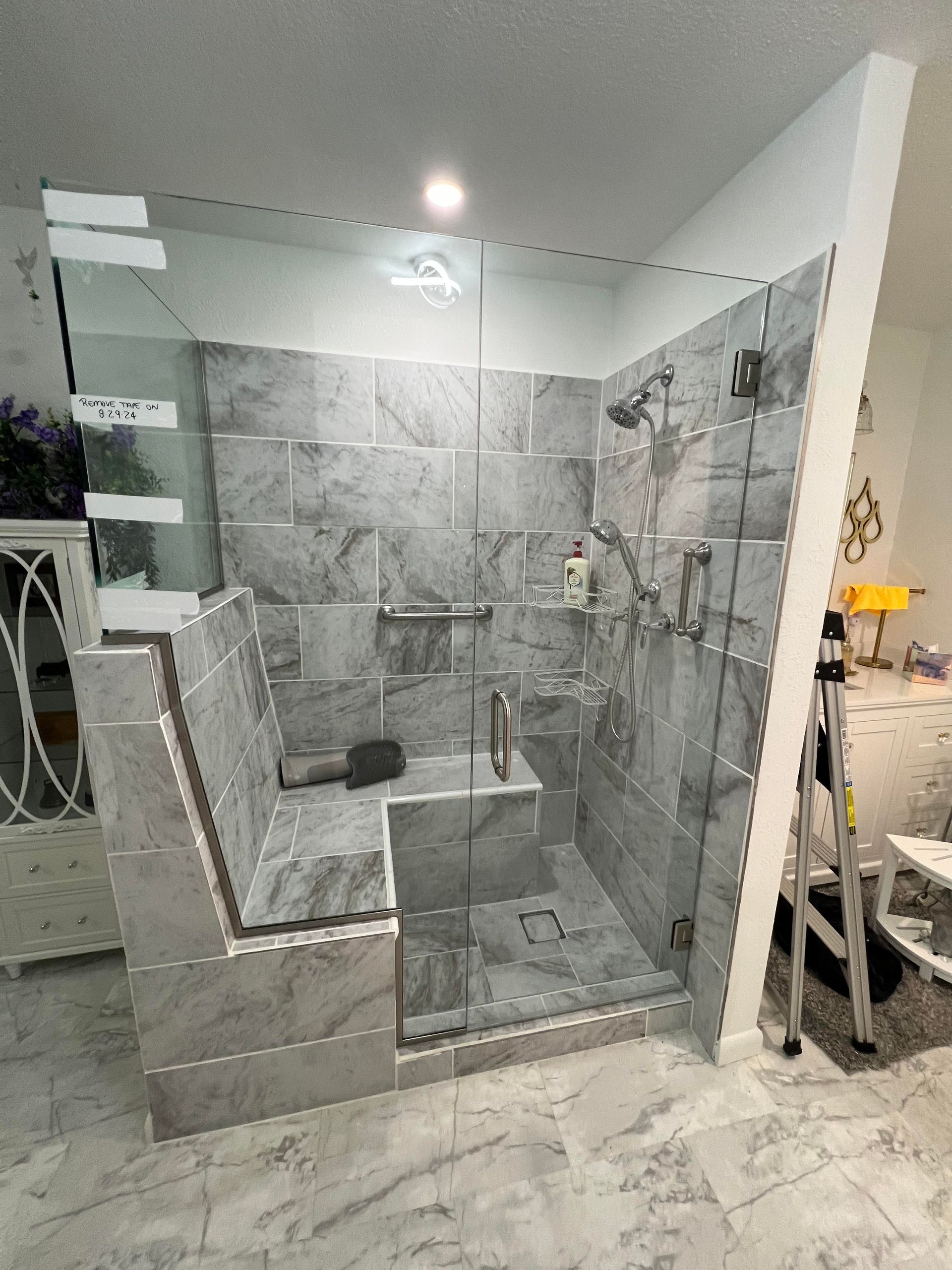 A bathroom with a walk in shower with a glass door.